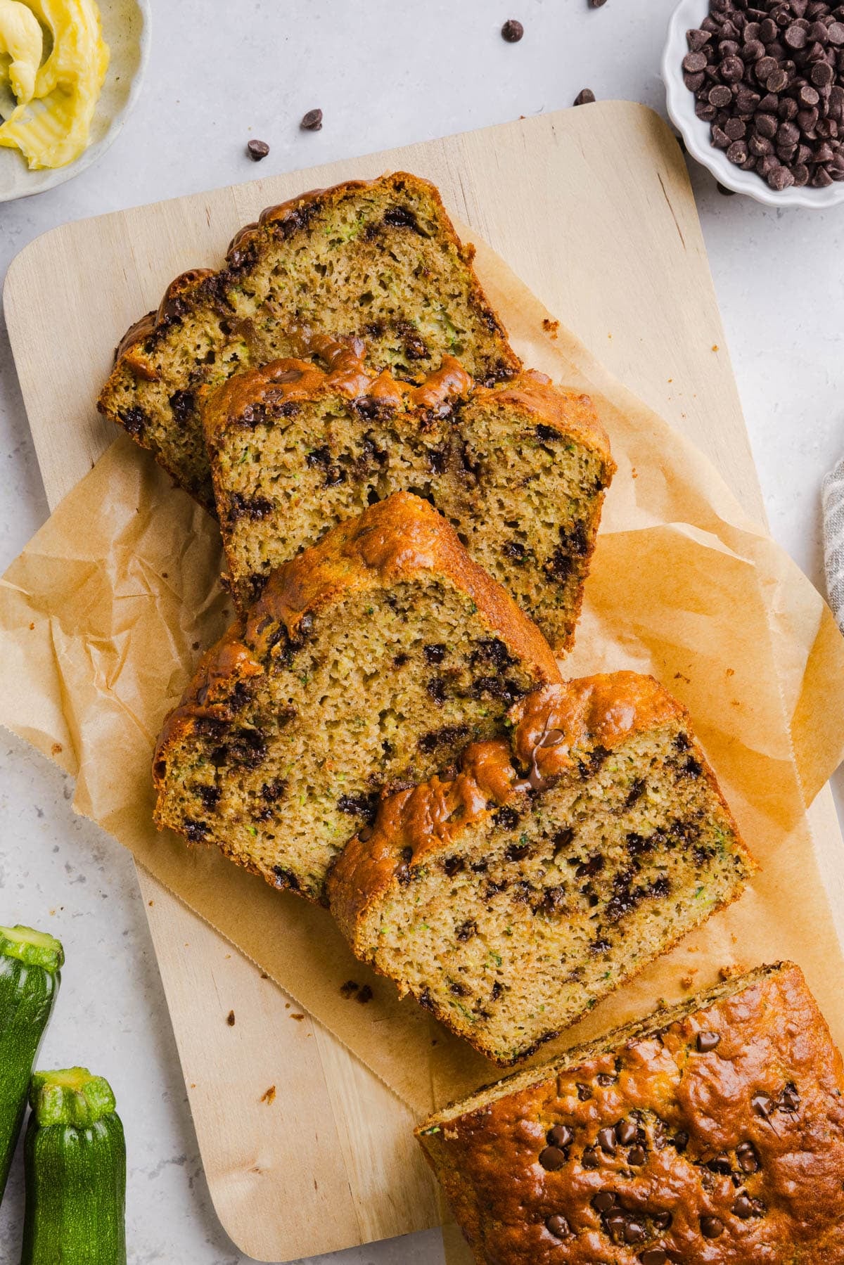 Four slices of protein zucchini bread on parchment paper on a countertop.
