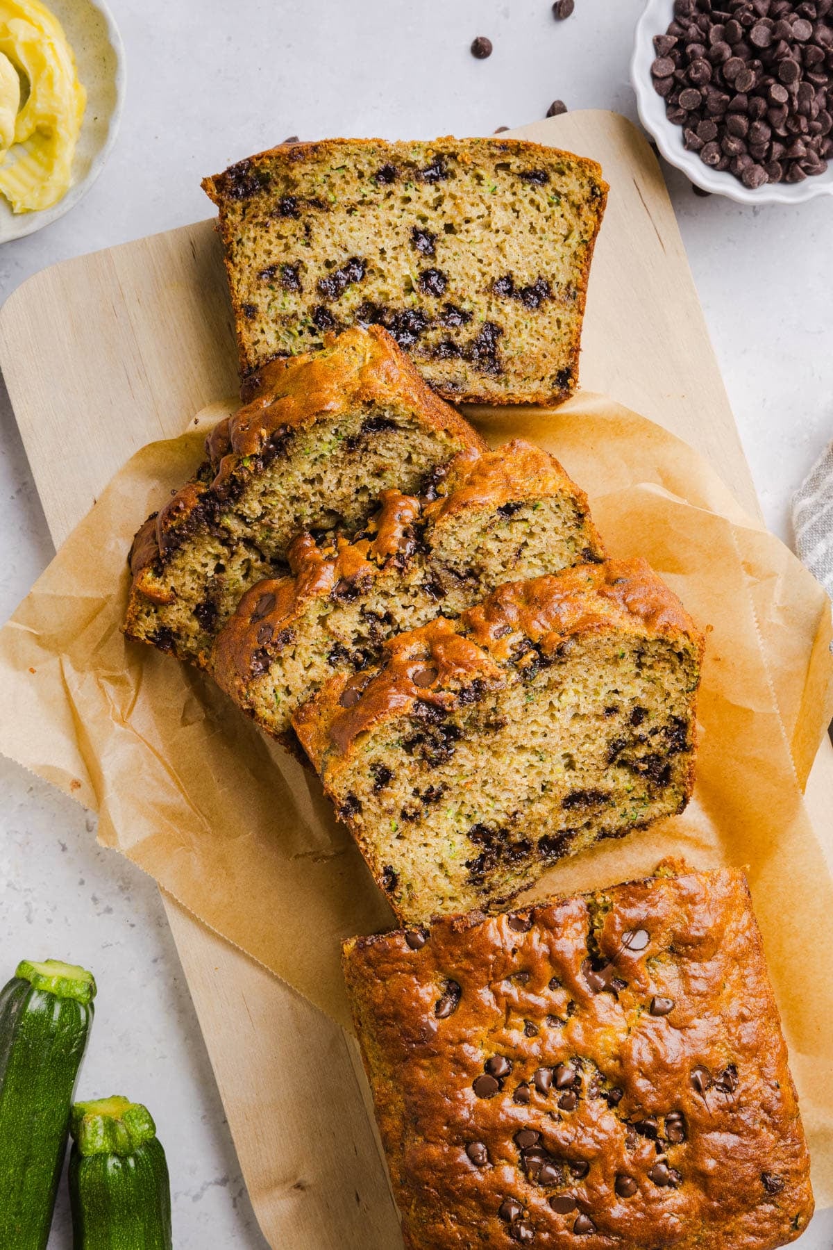Slices protein zucchini bread on a piece of parchment paper on a countertop.