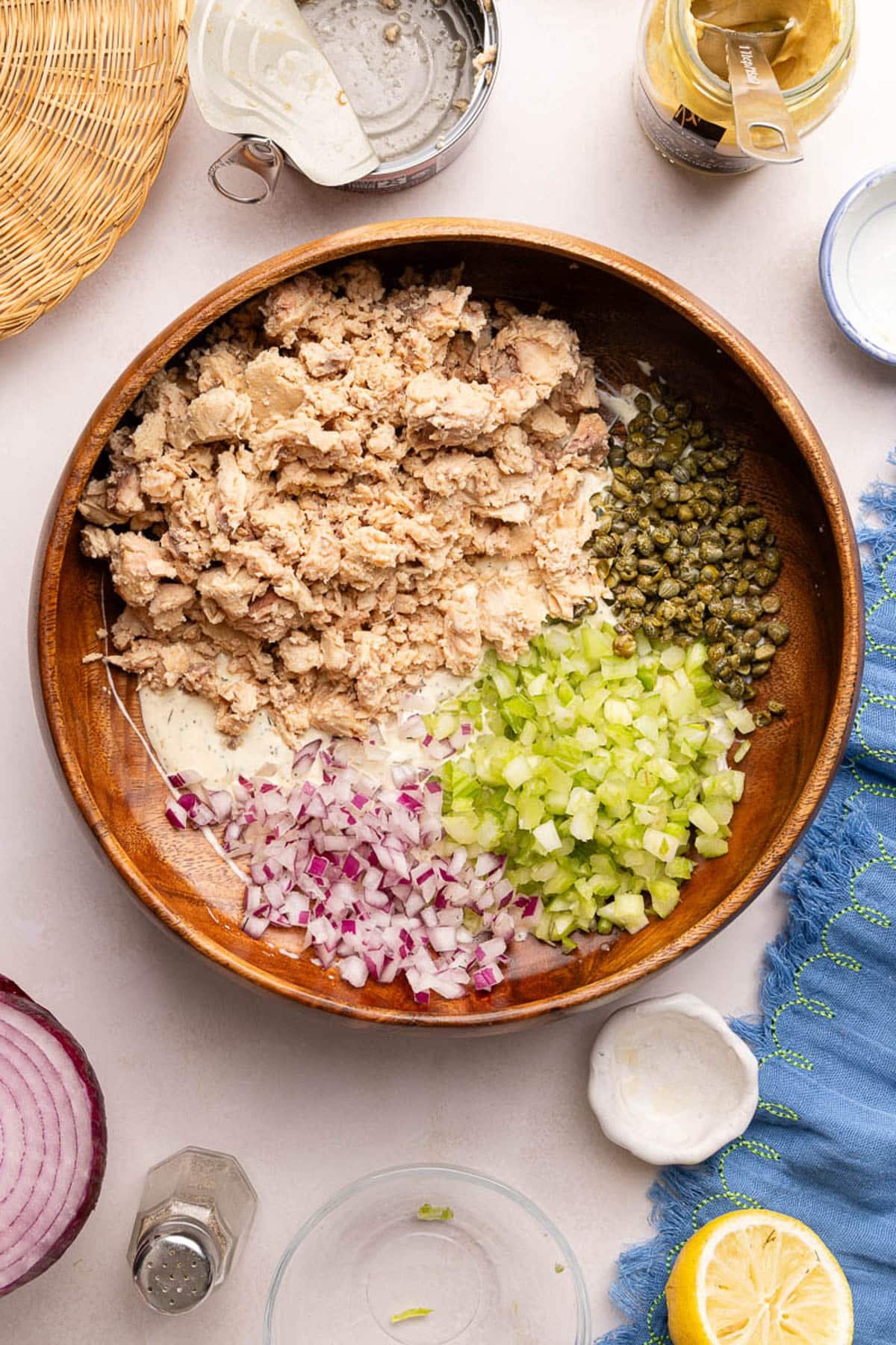 The salmon, celery, onion, and capers in the bowl on top of the combined mayo mixture.