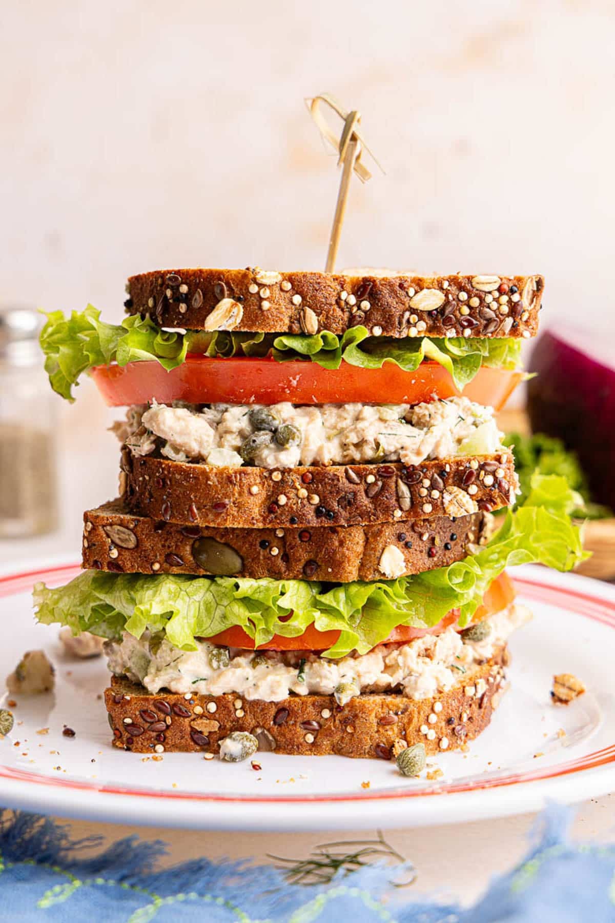 Two salmon salad sandwiches stack on top of each other on a plate.