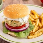 A spinach feta turkey burger on a white place with french fries.