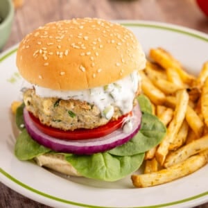A spinach feta turkey burger on a white place with french fries.