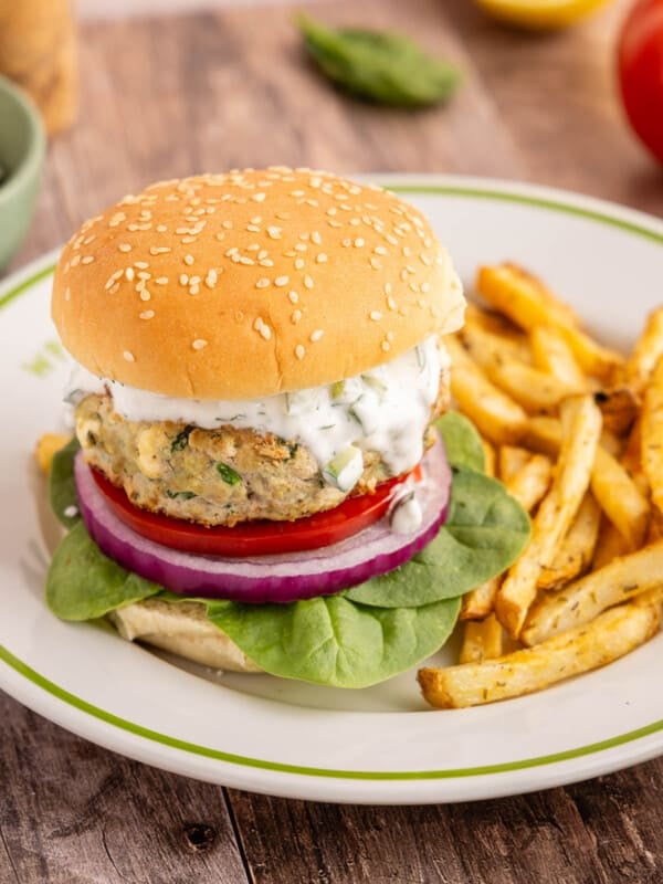 A spinach feta turkey burger on a white place with french fries.