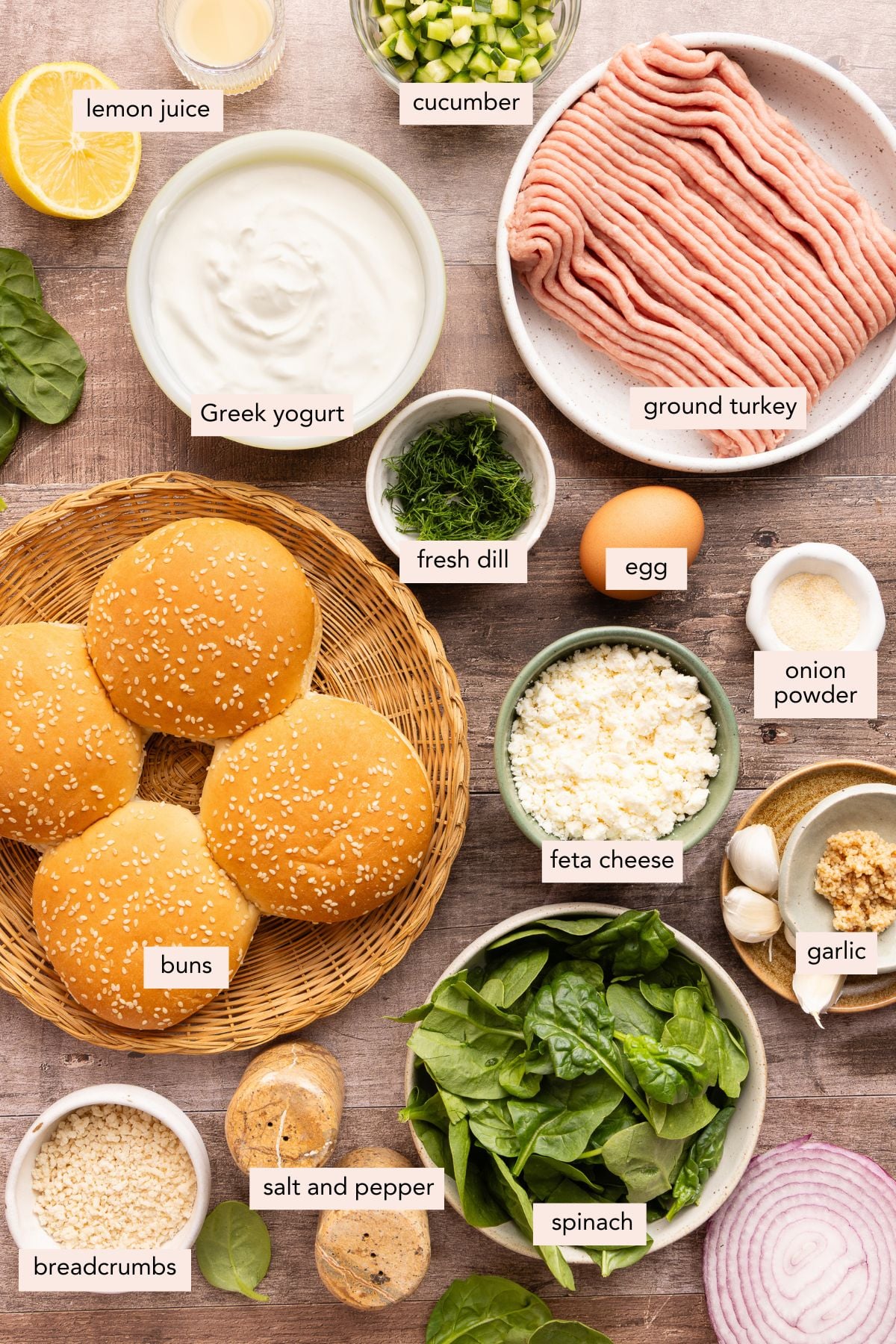 All of the ingredients for spinach feta turkey burgers in bowls on a countertop.