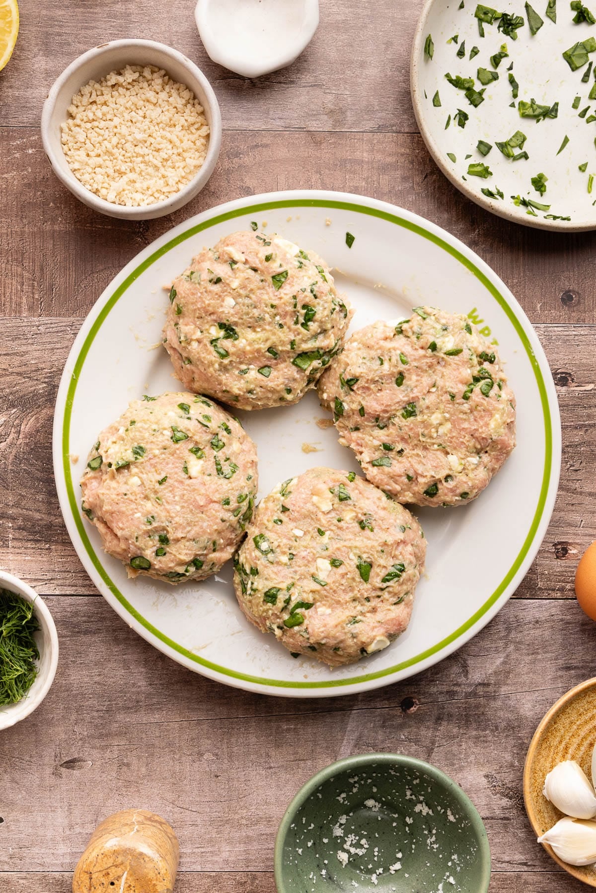 Four turkey burgers on a white plate after forming into the burgers before cooking.