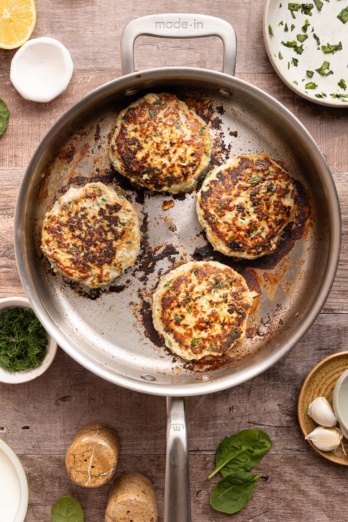 The four turkey burgers in a skillet after cooking.