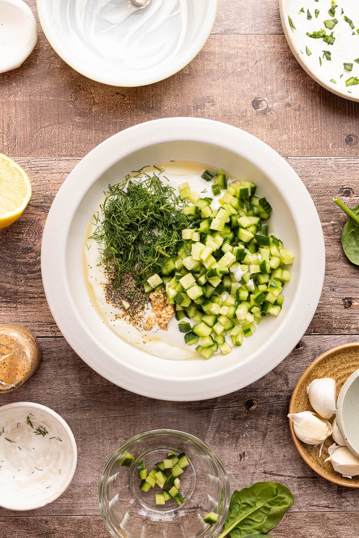 All of the ingredients for the tzatziki sauce in a white bowl on a countertop.