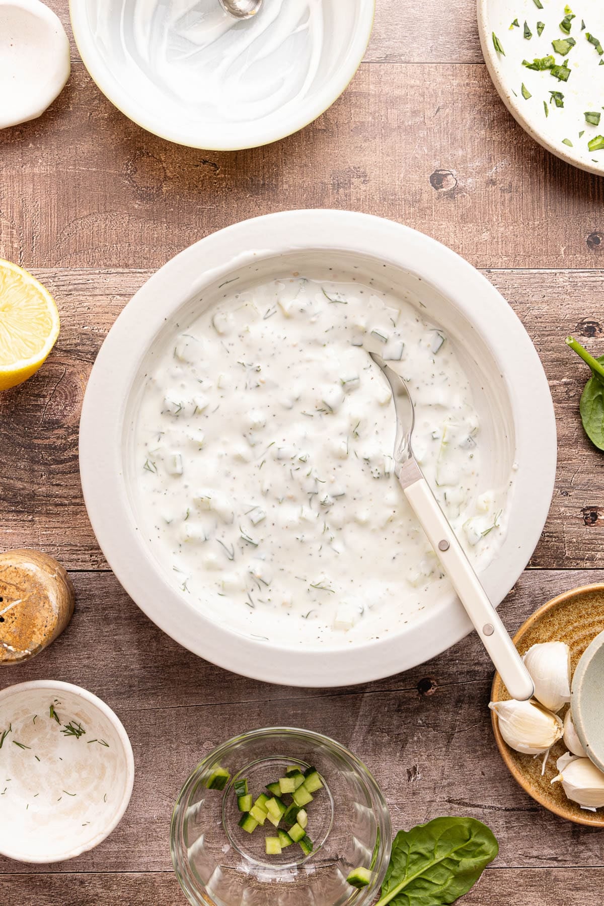 The mixed tzatiki in a white bowl with a spoon.