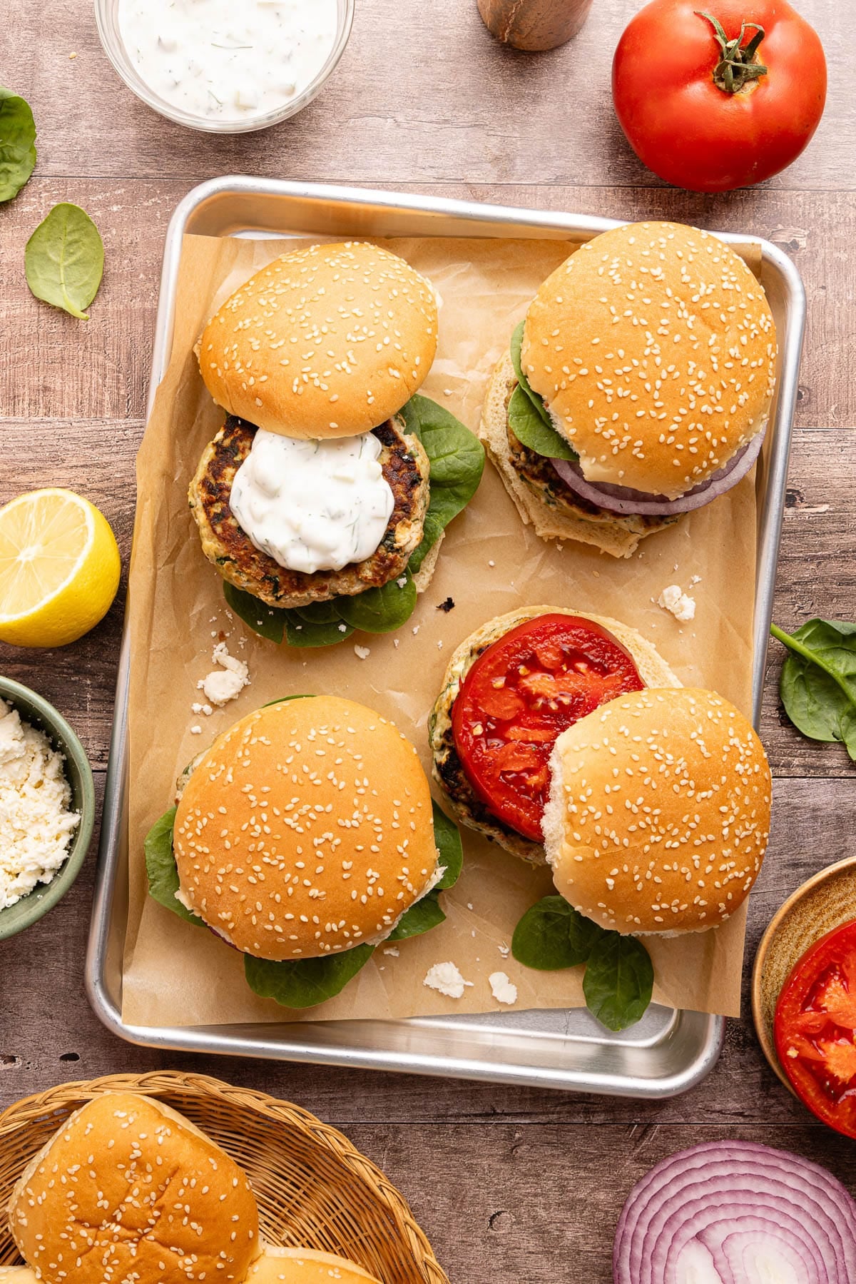 Four spinach feta turkey burgers assembled on a baking sheet.