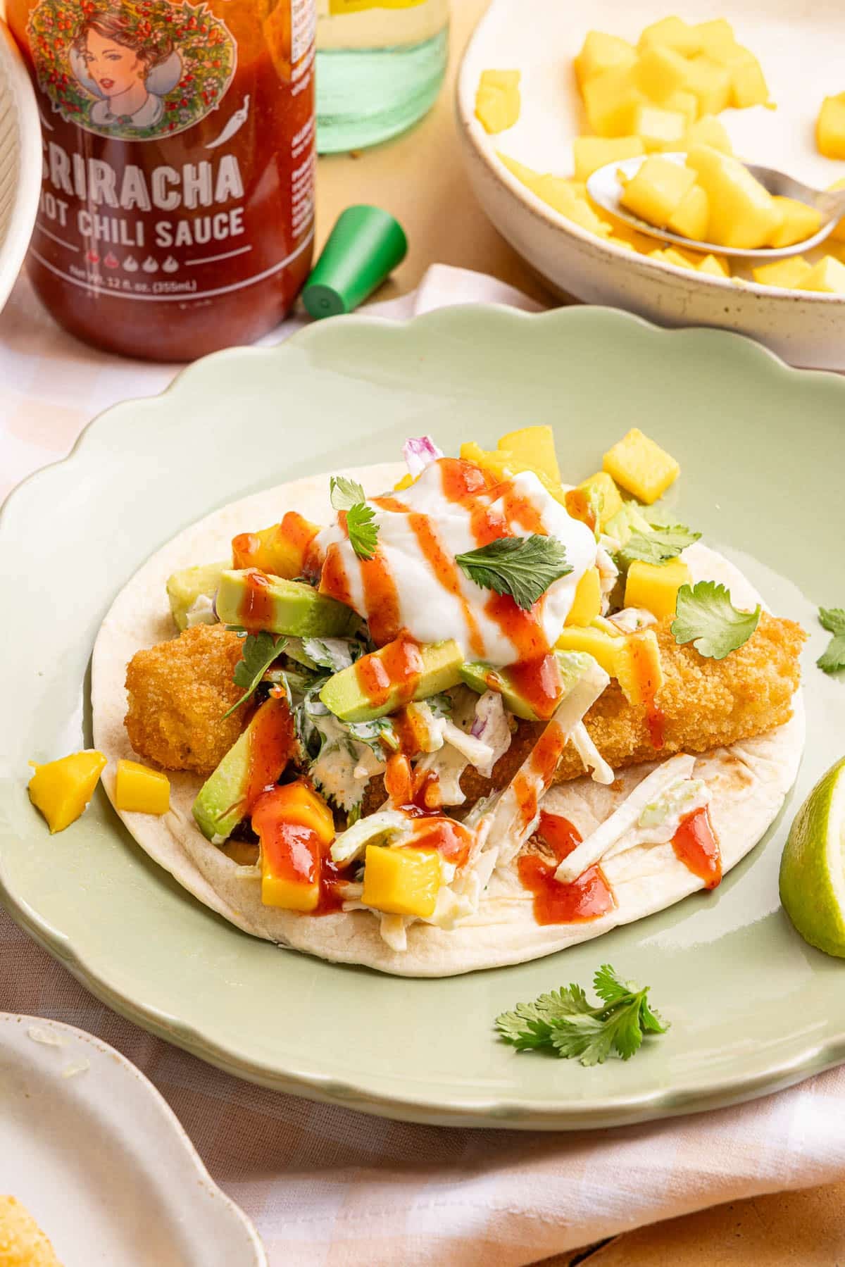 A fish stick taco on a green plate for serving.