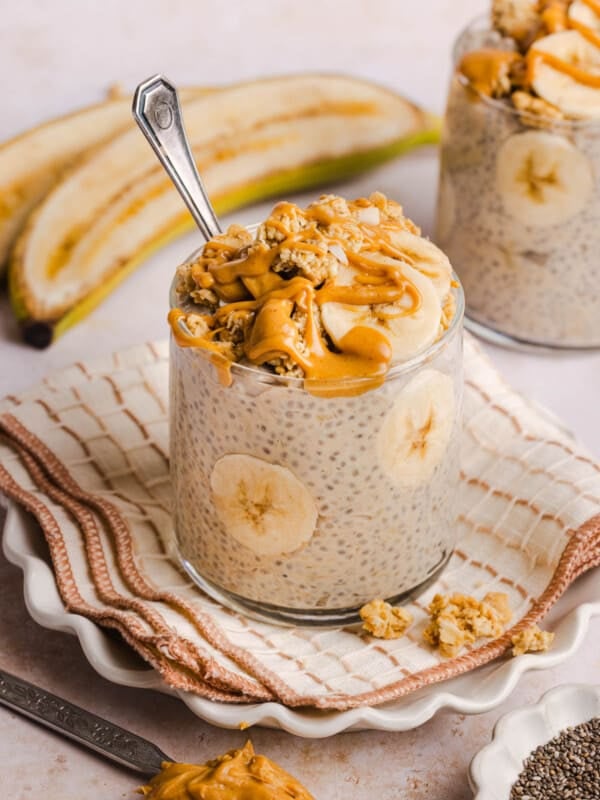 Peanut butter banana chia pudding in a glass on a napkin on a countertop.