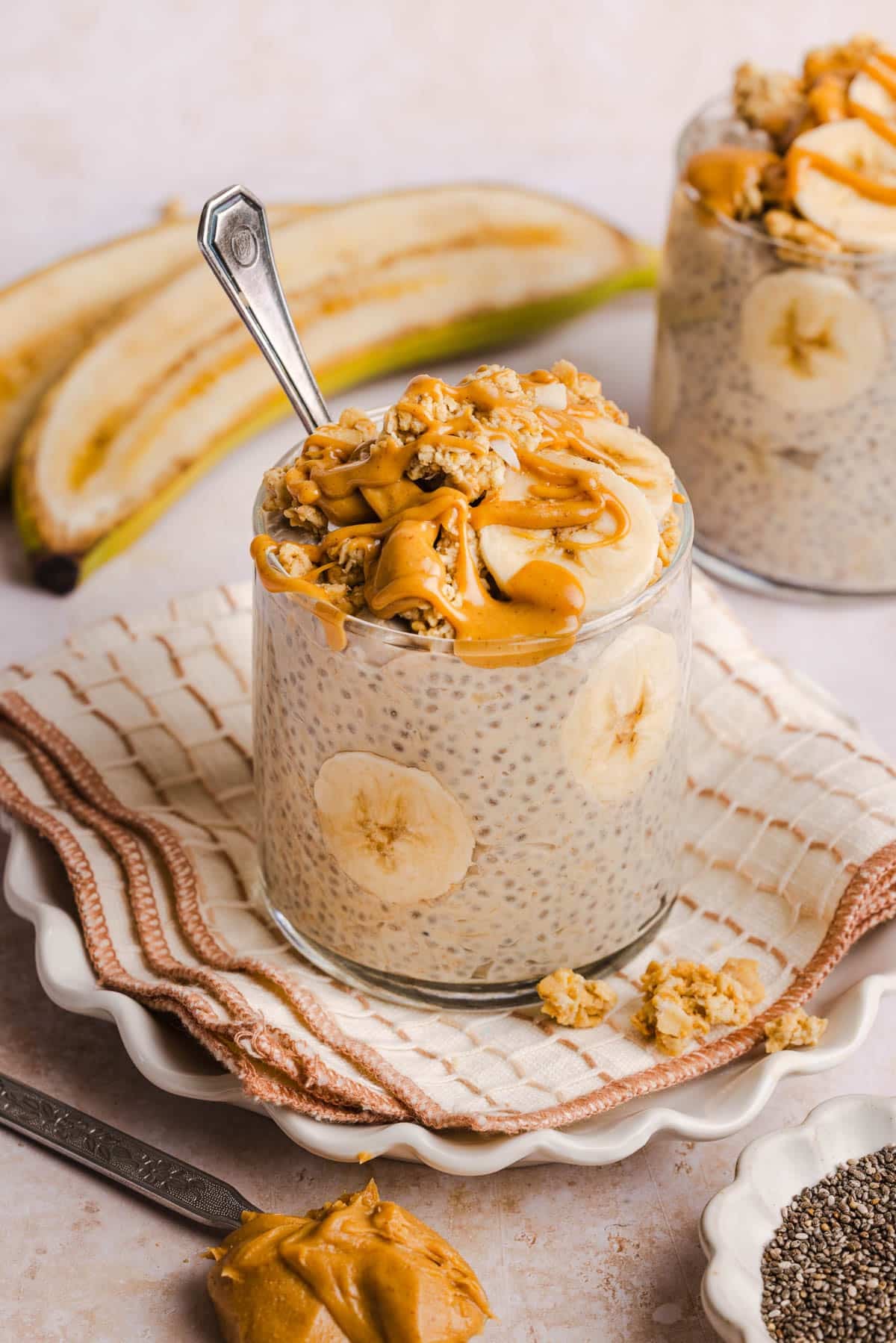 Peanut butter banana chia pudding in a glass on a napkin on a countertop.