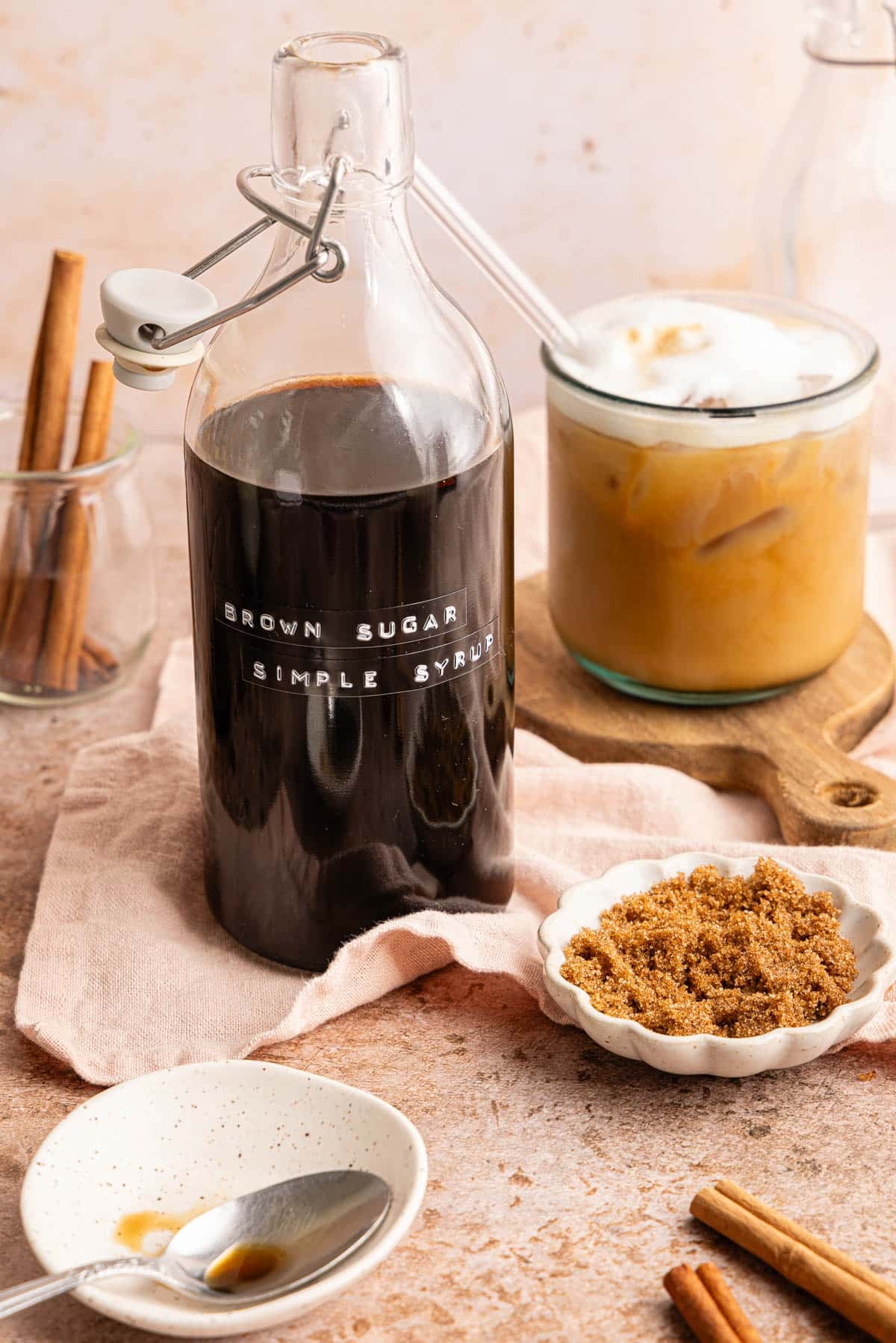 A glass pours the brown sugar simple syrup into a glass of iced coffee.