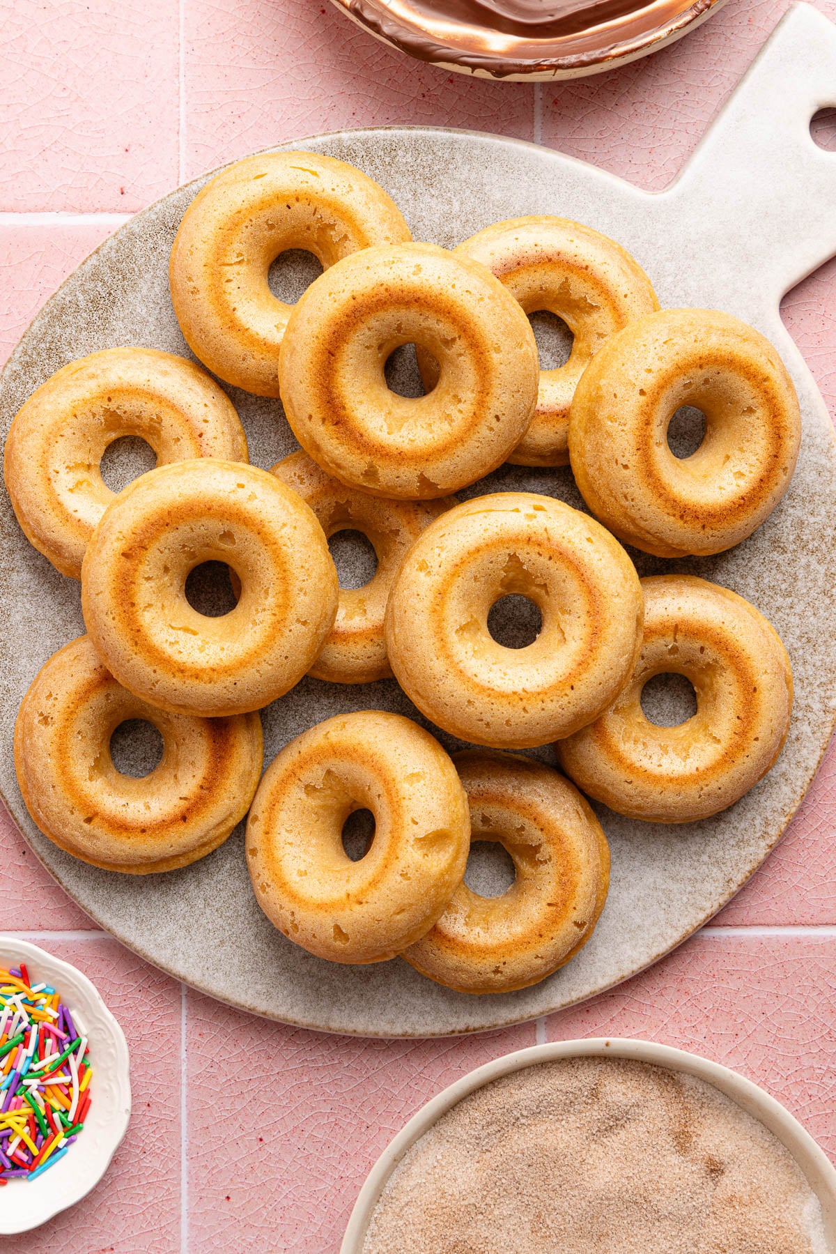 The baked donuts on a serving platter before adding the toppings.