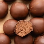 A cut cottage cheese truffle sits on top of a stack of remaining cottage cheese truffles.
