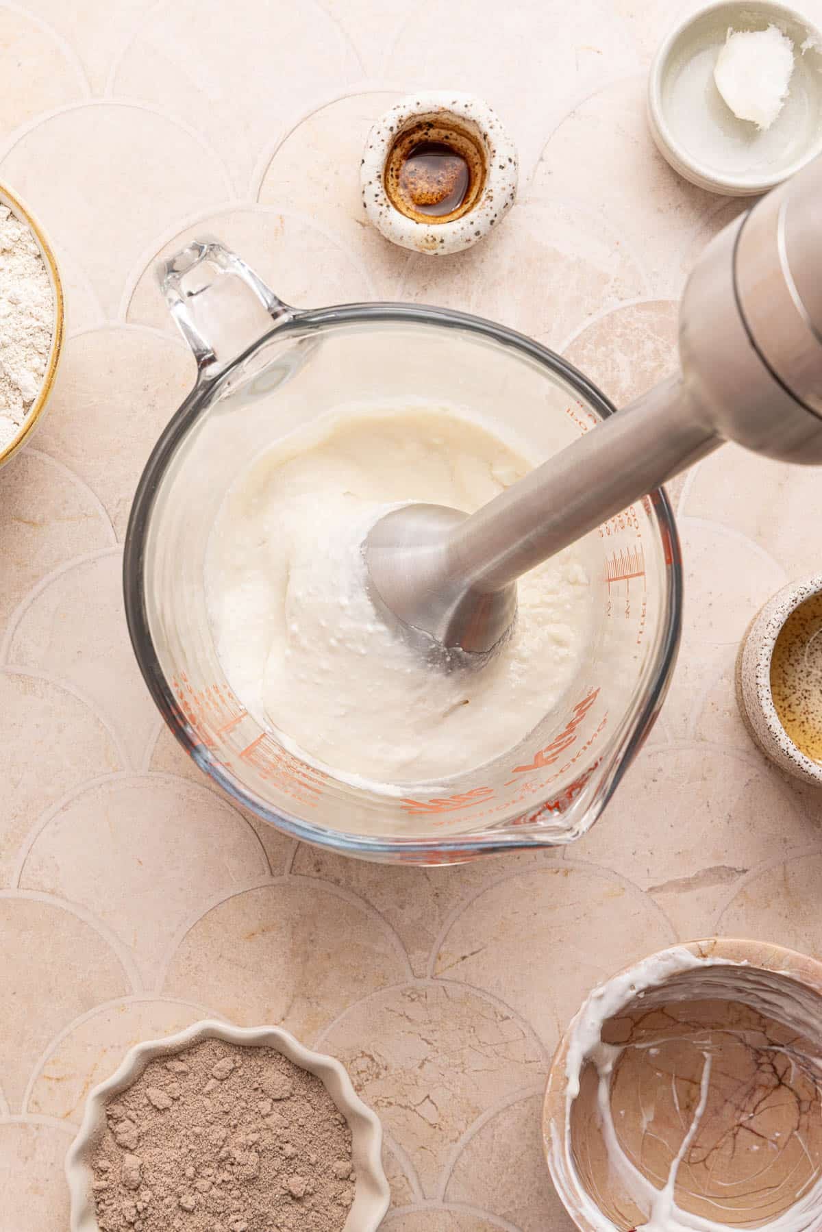 An immersion blender in the glass measuring cup while blending.
