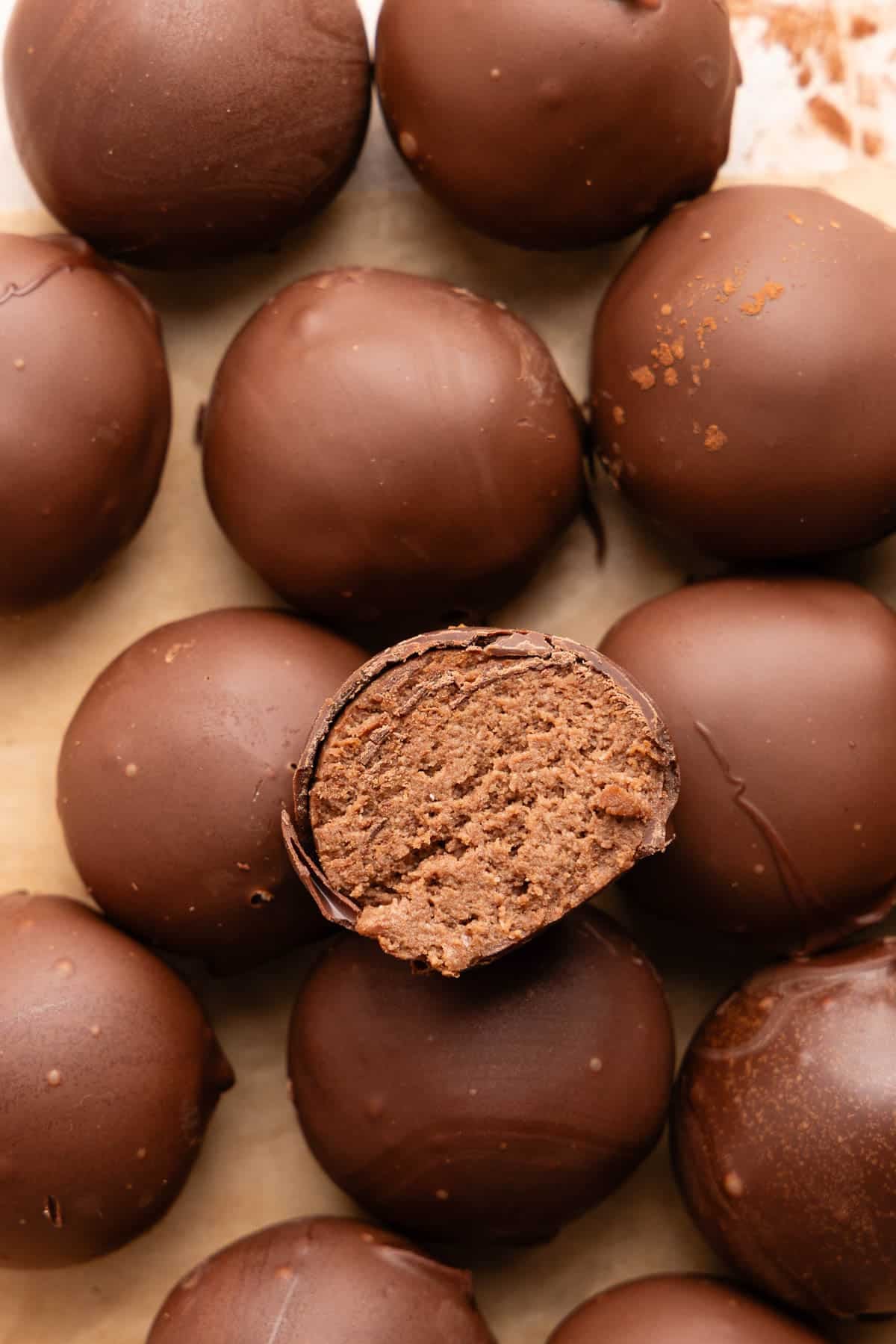 A cut cottage cheese truffle sits on top of a stack of remaining cottage cheese truffles.