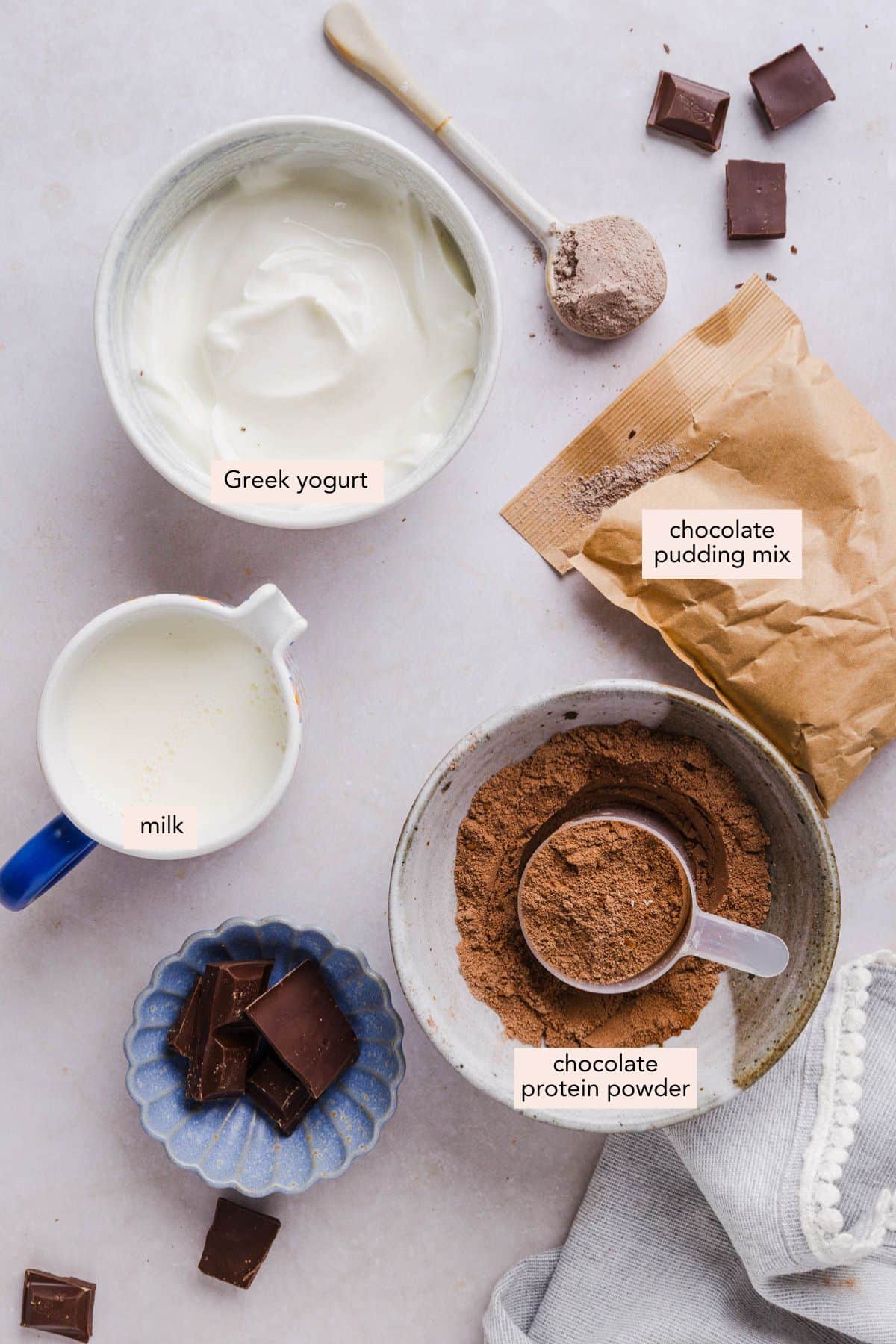 All of the ingredients for high protein chocolate pudding in bowls on a countertop.