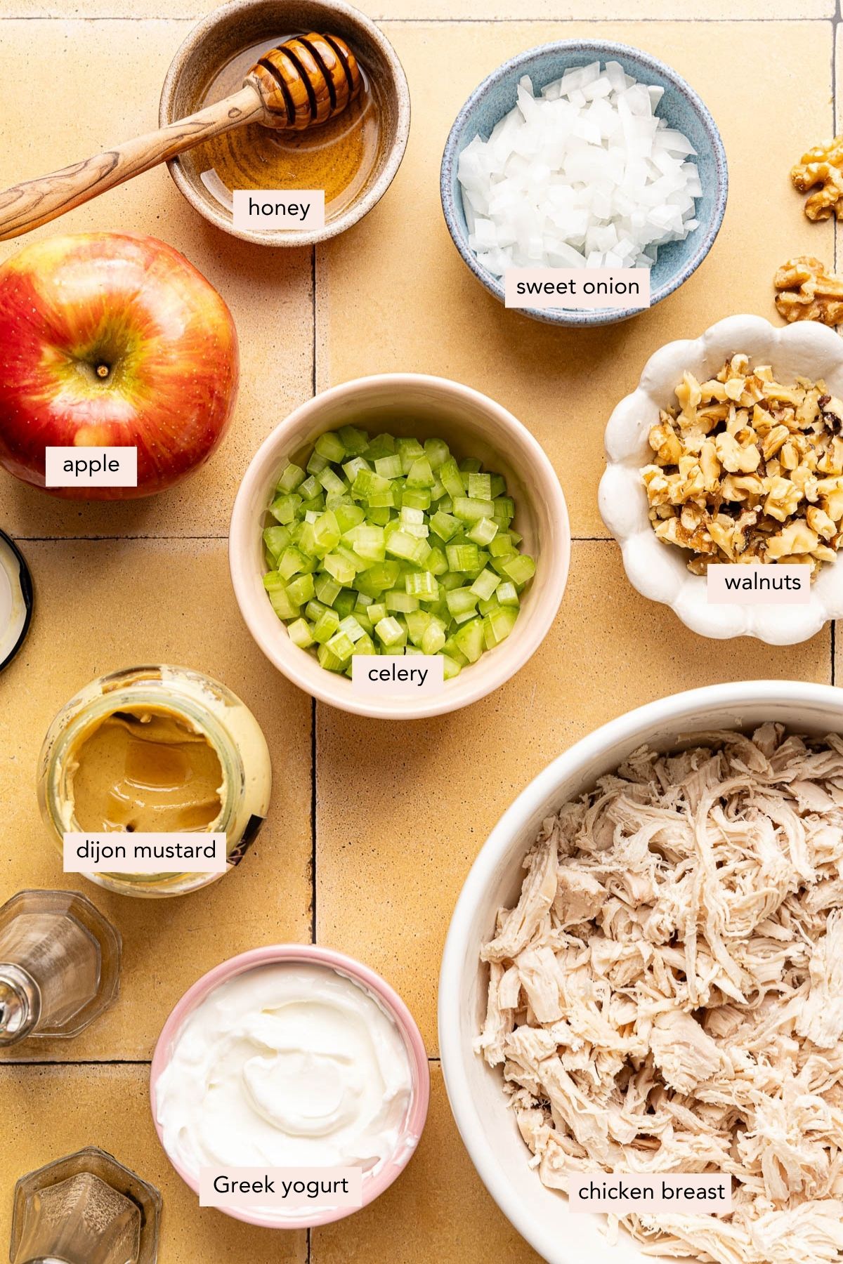 All of the ingredients for honey mustard chicken salad in bowls on a countertop.
