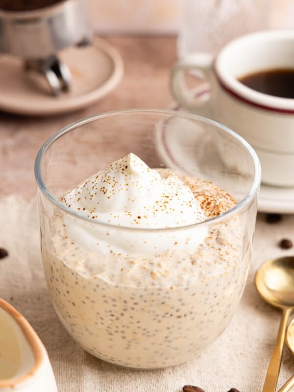 The coffee overnight oats with whipped cream or greek yogurt on top in a jar on a countertop.
