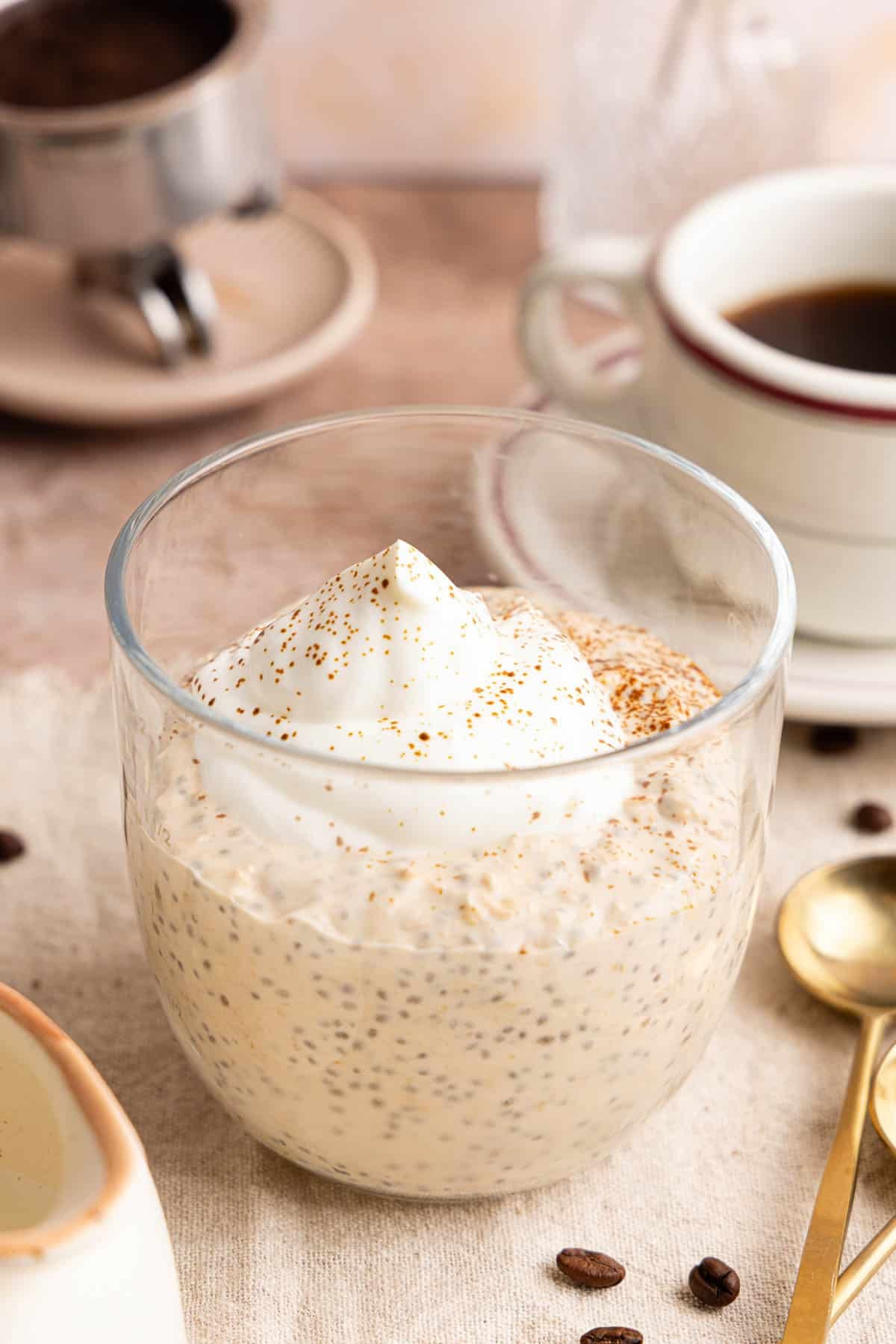 The coffee overnight oats with whipped cream or greek yogurt on top in a jar on a countertop.