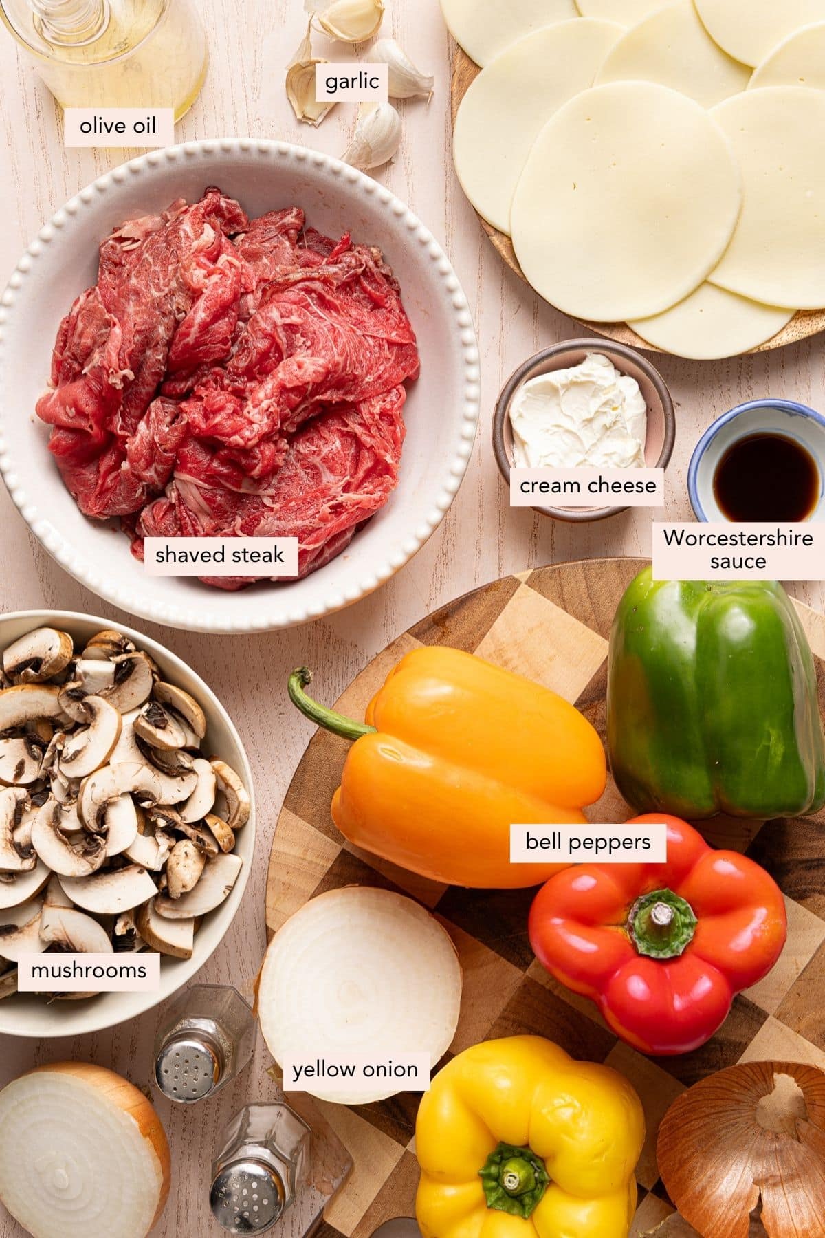 All of the ingredients for philly cheesesteak stuffed peppers in bowls on a countertop.