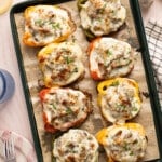 The cooked philly cheesesteak stuffed peppers on the parchment paper on the sheet pan after baking.