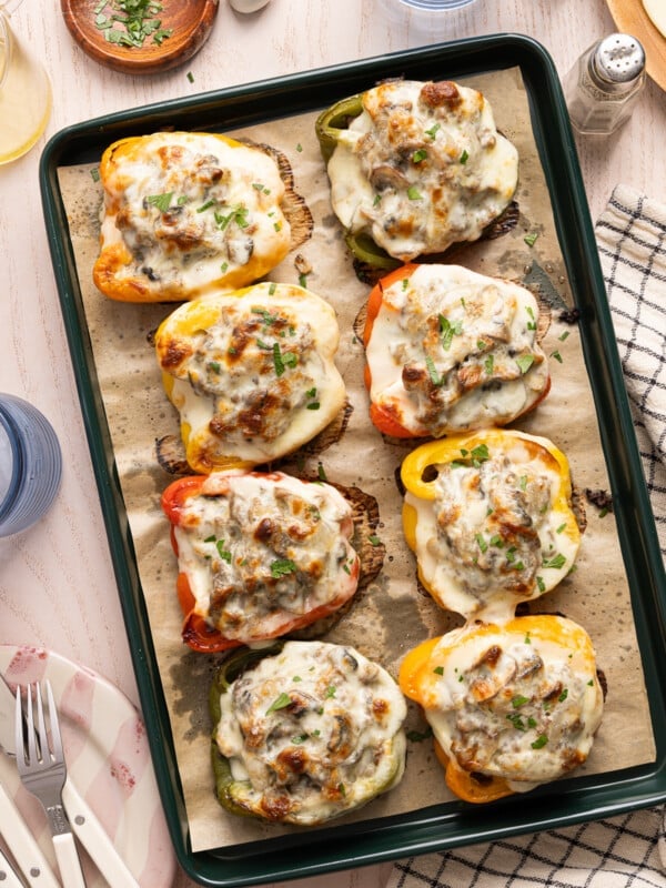 The cooked philly cheesesteak stuffed peppers on the parchment paper on the sheet pan after baking.