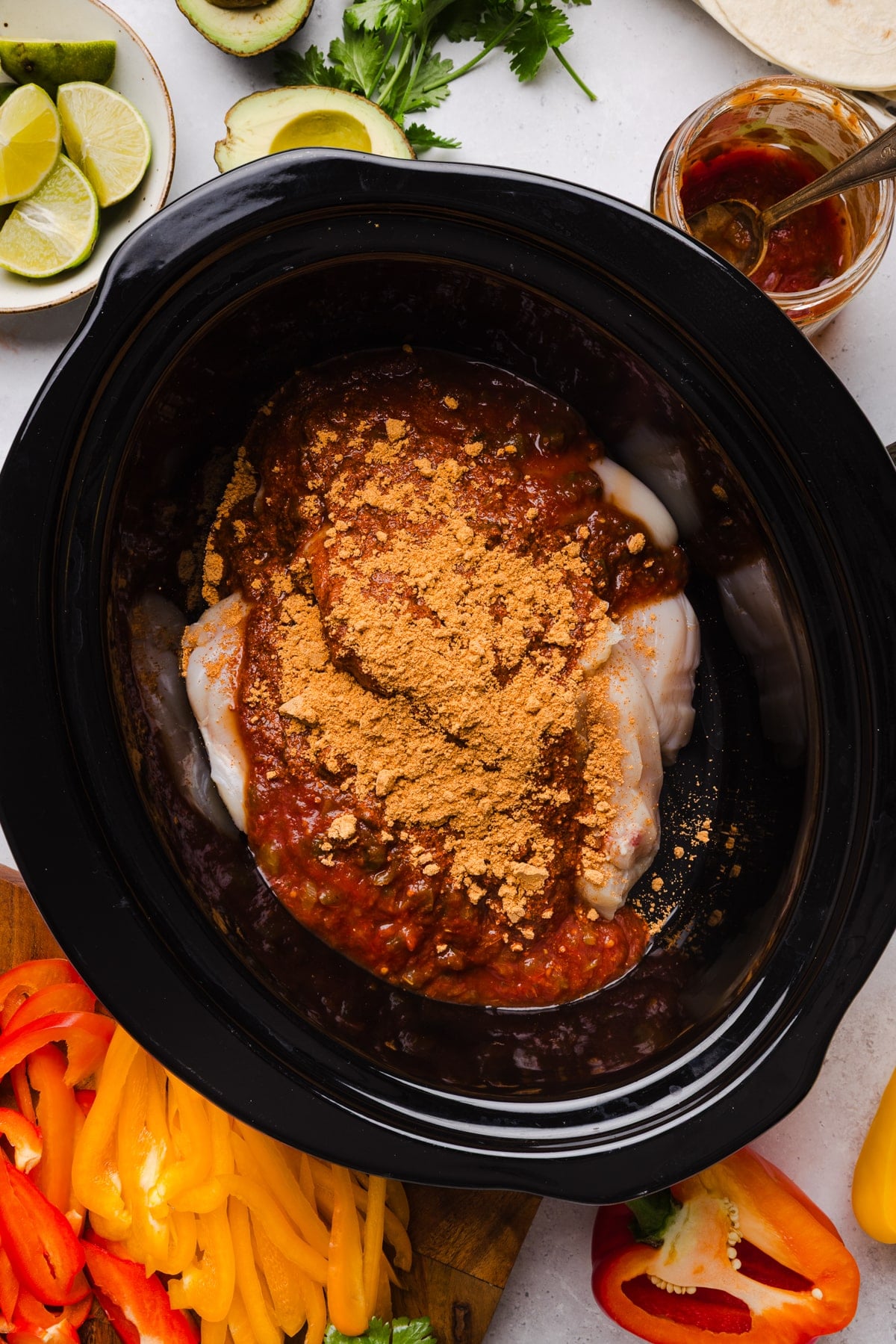 The chicken breast, salsa, taco seasoning, and lime juice in a slow cooker.