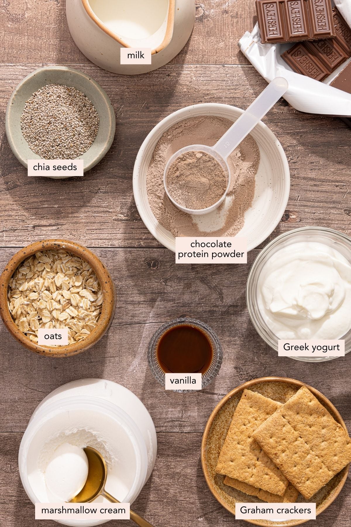 All of the ingredients for s'mores overnight oats in bowls on a countertop.