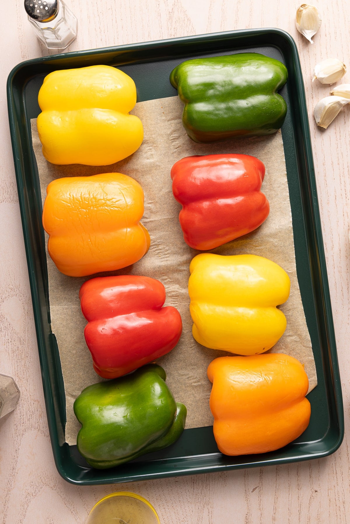 The cut bell peppers cut-size down on a piece of parchment paper on a baking sheet before roasting in the oven.