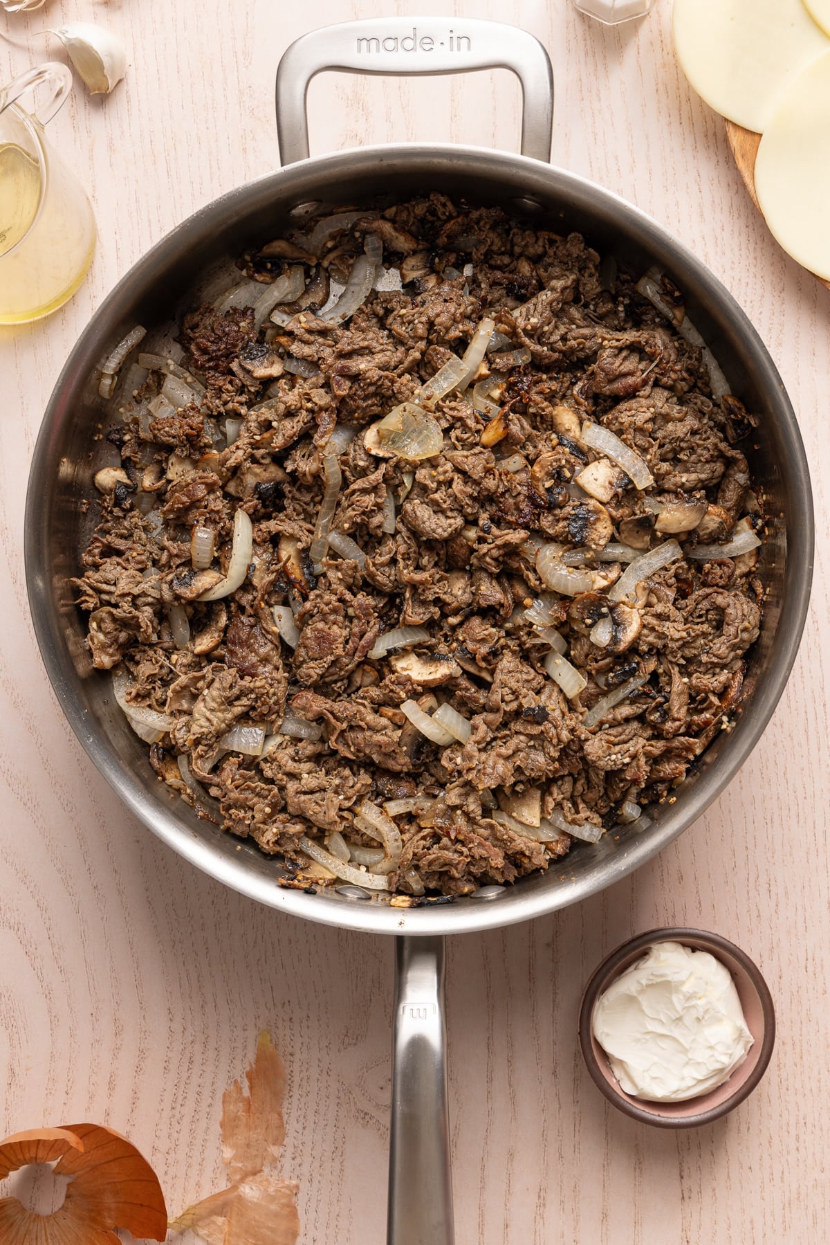 The shaved steak in the pan with the cooked onions.