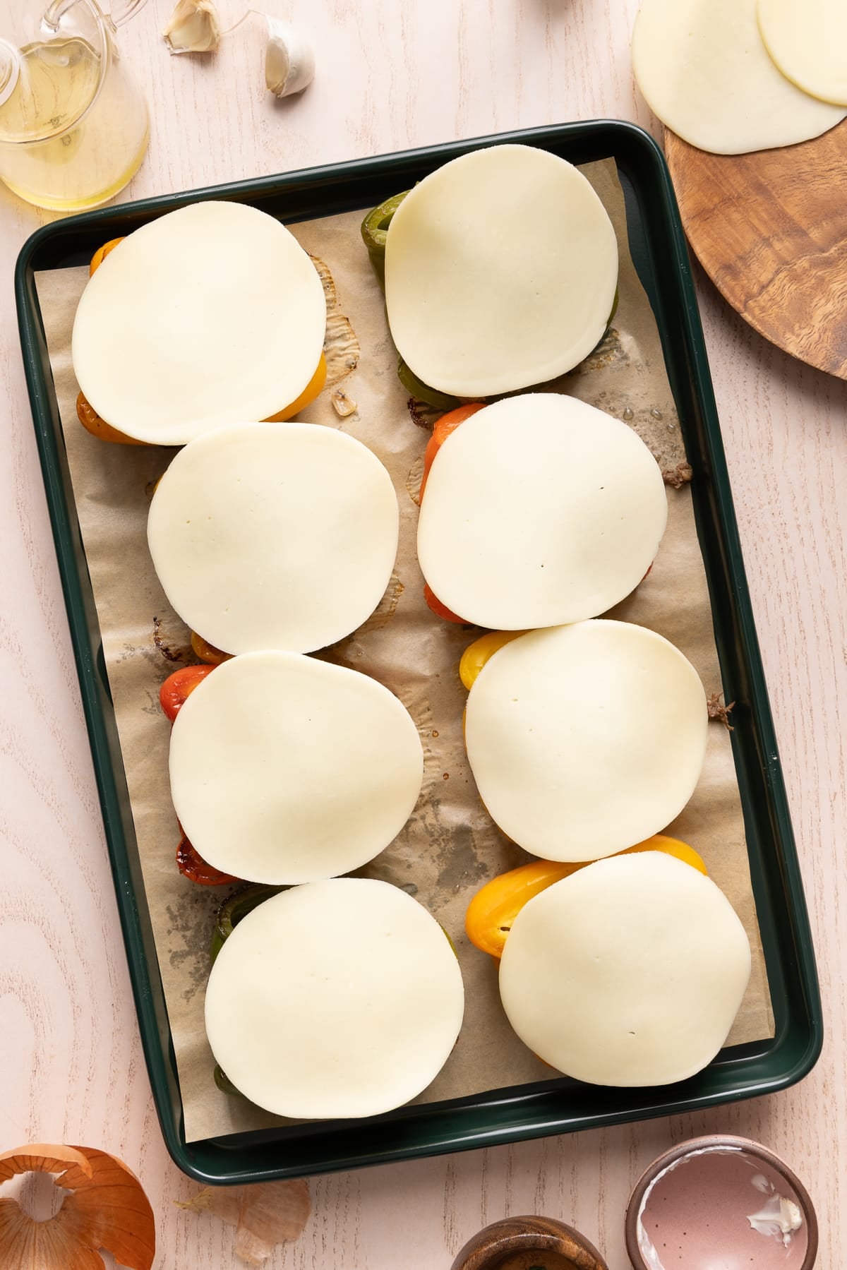 The stuffed peppers on the sheet pan with the provolone cheese on top of each pepper before baking.