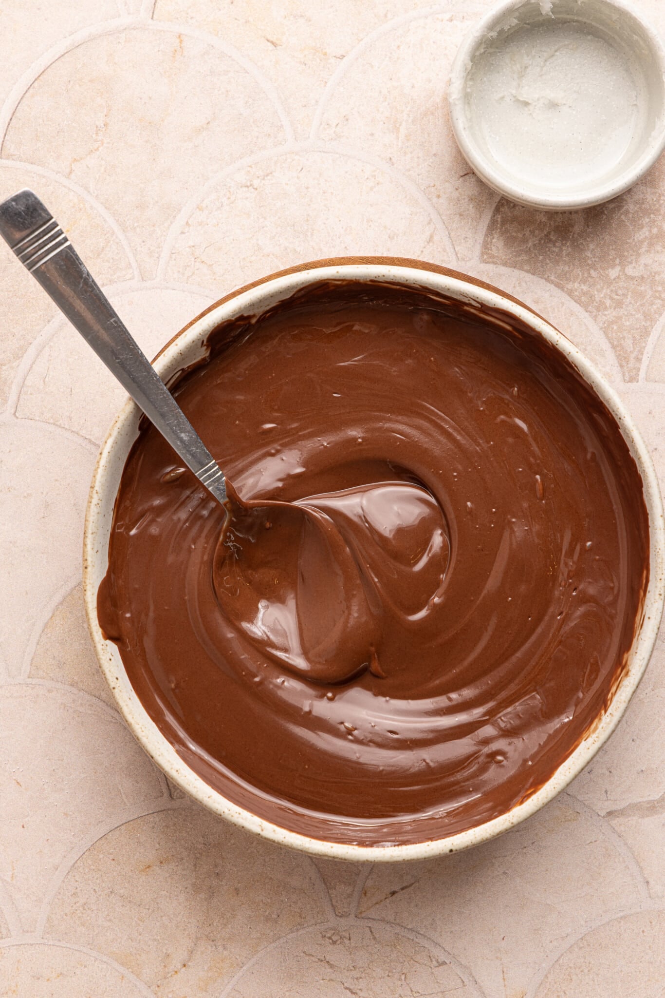 Chocolate melted in a white bowl with a spoon.