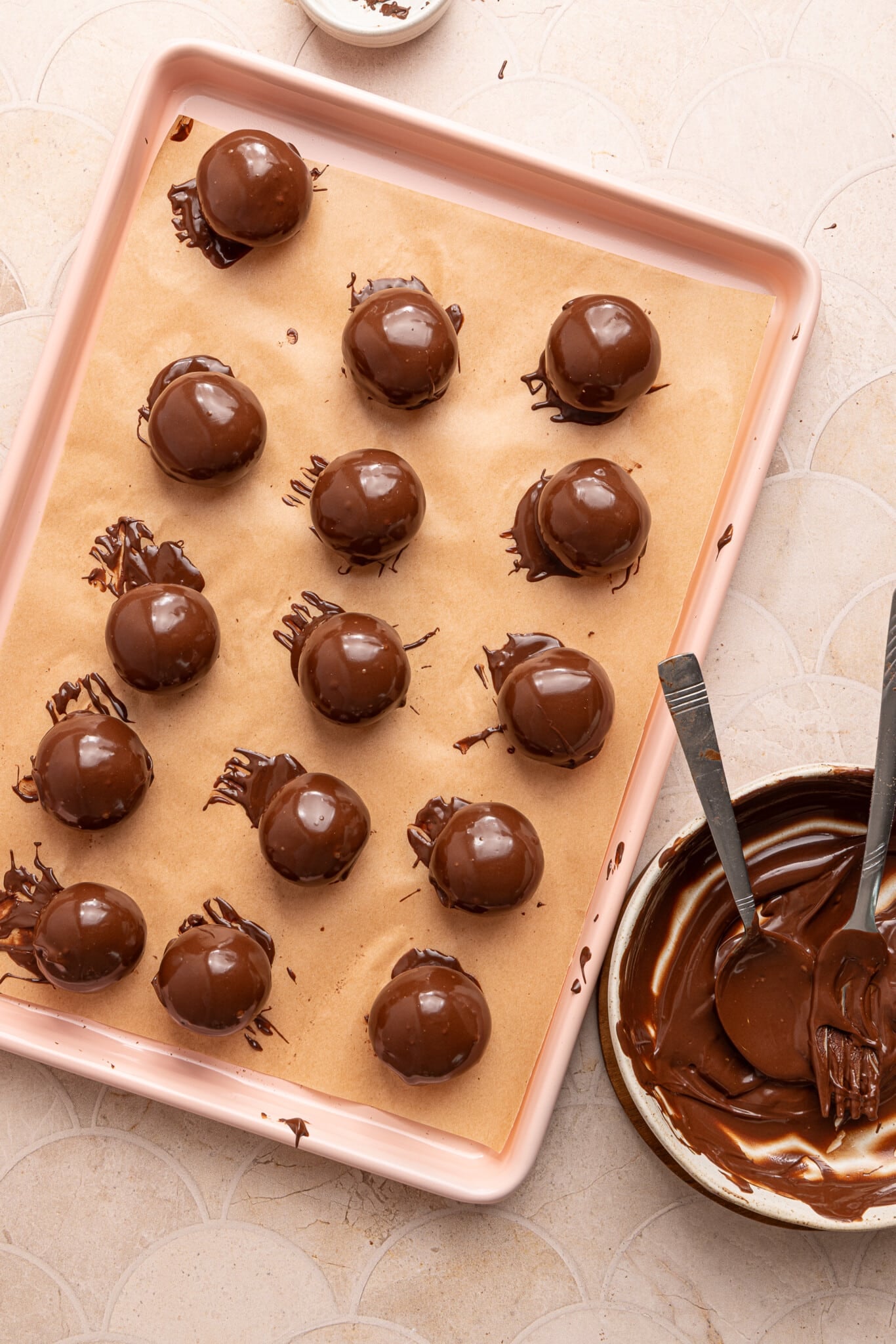 Cottage cheese truffles dipped in chocolate on a parchment paper lined baking sheet.