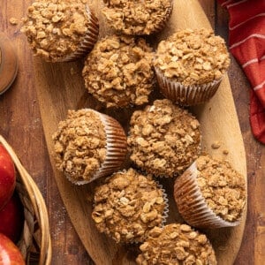 Apple cinnamon muffins on a wooden cutting board after baking.