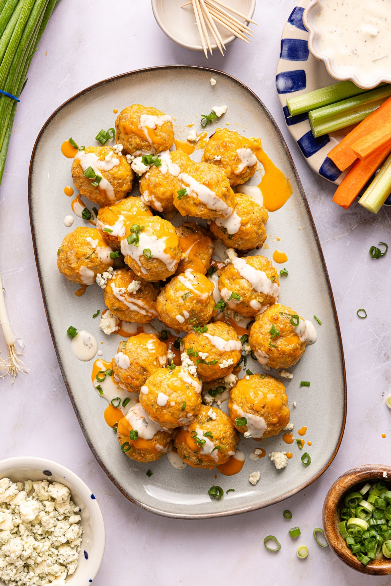 A white serving platter with buffalo chicken meatballs with a drizzle of ranch on top.