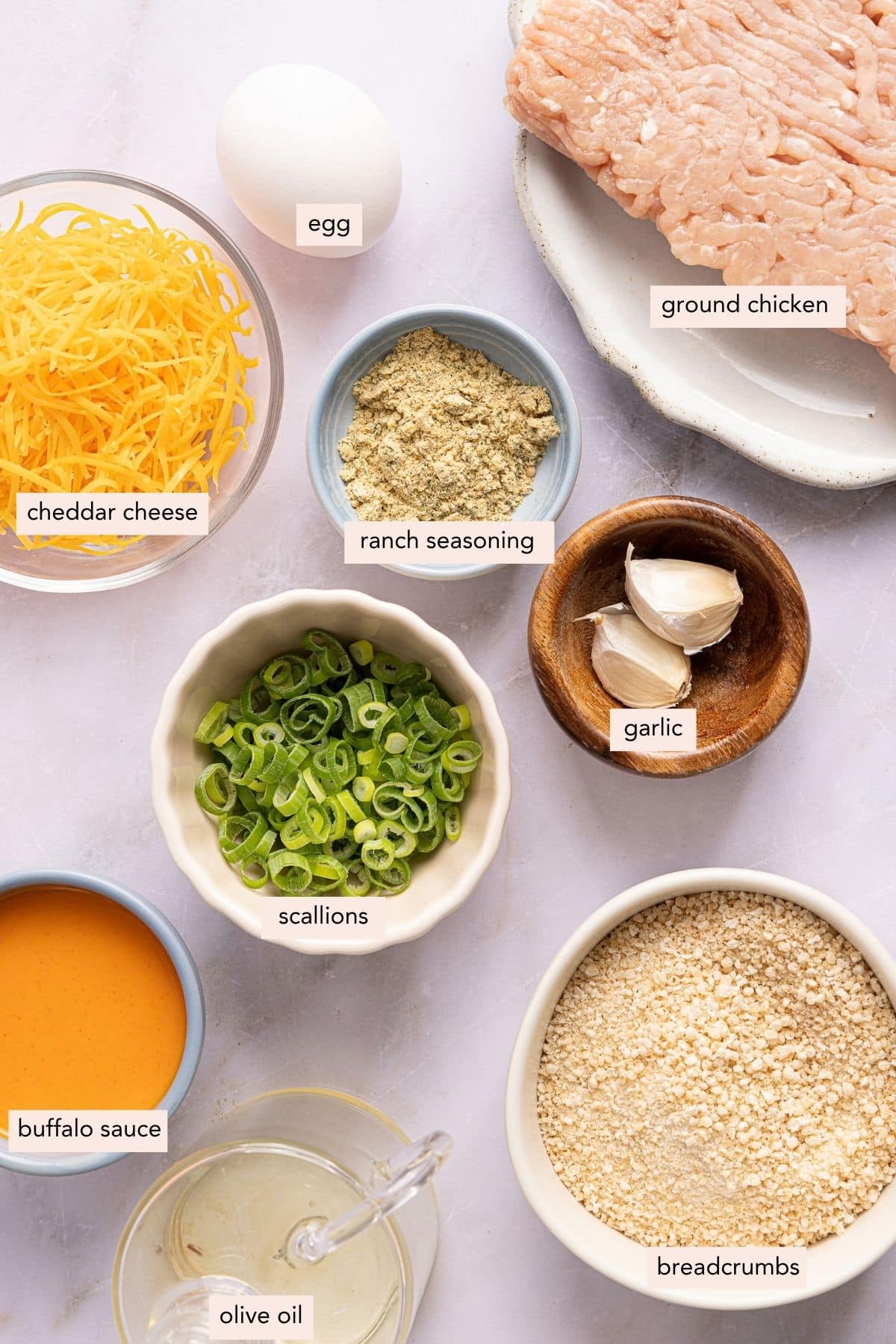 All of the ingredients for buffalo chicken meatballs in bowls on a counter.