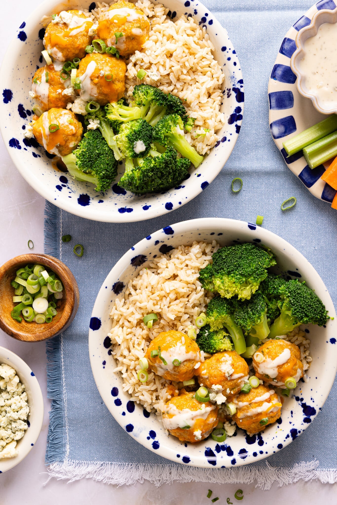 Two bowls of buffalo chicken meatballs served with rice and broccoli.