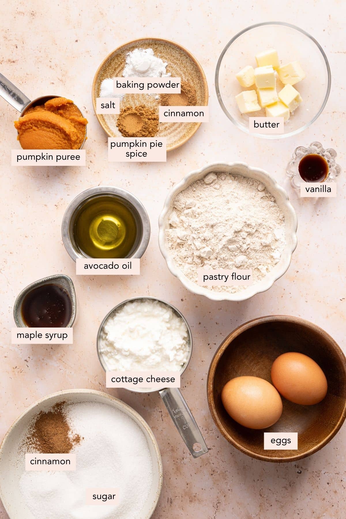 All of the ingredients for baked pumpkin cottage cheese donuts in bowls on a countertop.