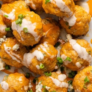 Baked buffalo chicken meatballs stacked and drizzled with ranch dressing.