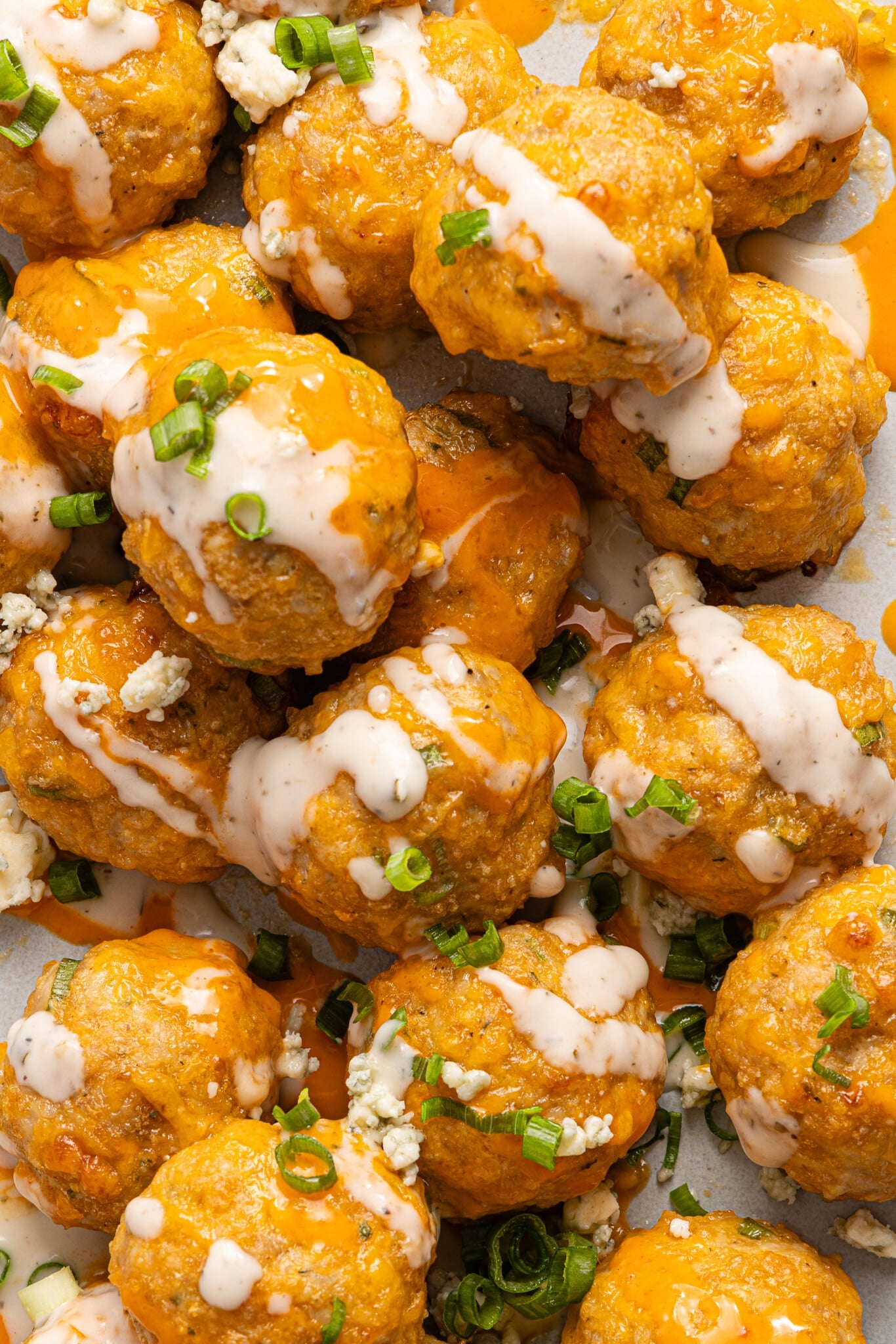 Baked buffalo chicken meatballs stacked and drizzled with ranch dressing.