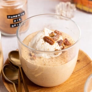 Pumpkin chia pudding in a glass bowl with with Greek yogurt, pecans, and crushed graham crackers.