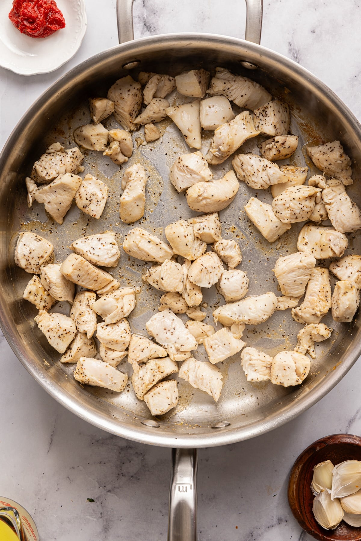 The chicken cooking in the skillet.
