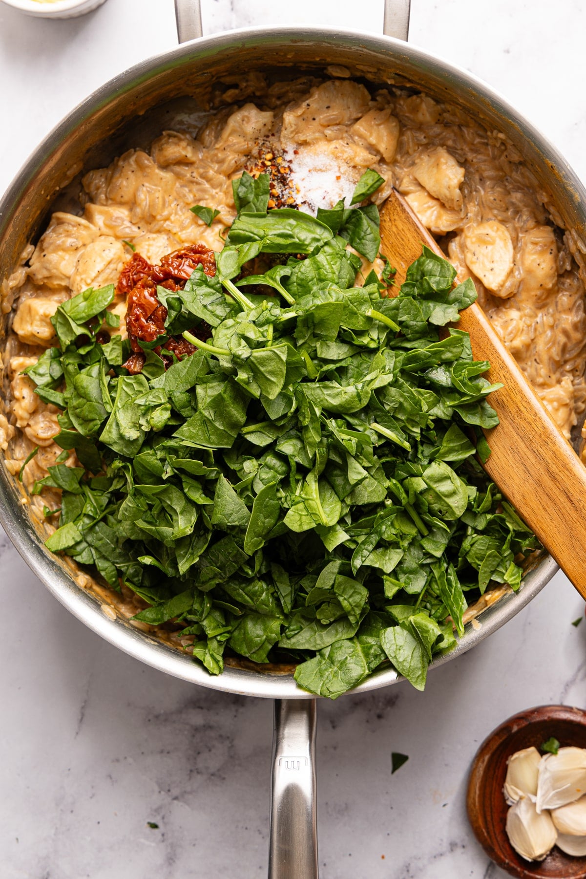 The tomatoes, spinach, salt, pepper, and red pepper flakes in the skillet before stirring everything together.