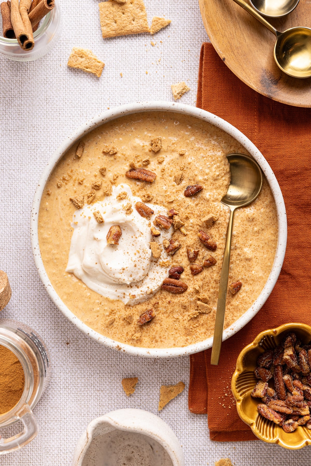 Pumpkin chia pudding in a white a white bowl on a countertop with a spoon in it.