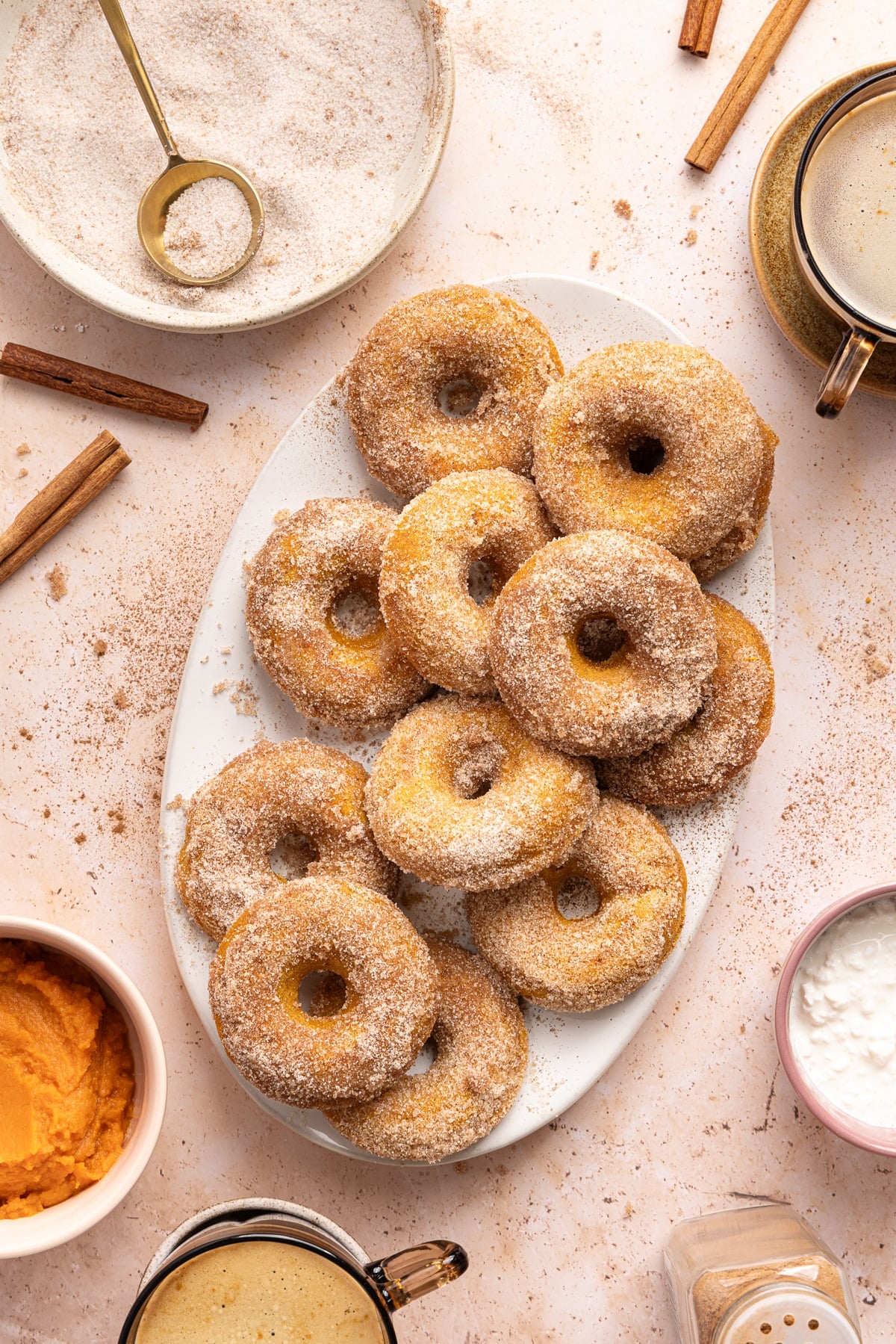 A dozen baked pumpkin cottage cheese donuts on a white serving platter on a countertop.