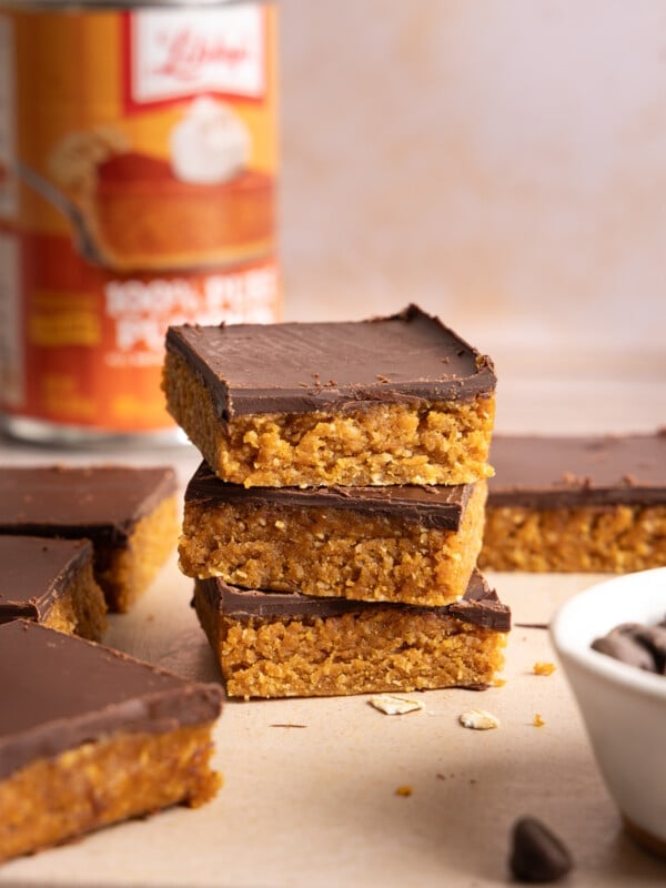 A stack of three No Bake Chocolate and Peanut Butter Pumpkin Oat Bars on a countertop.