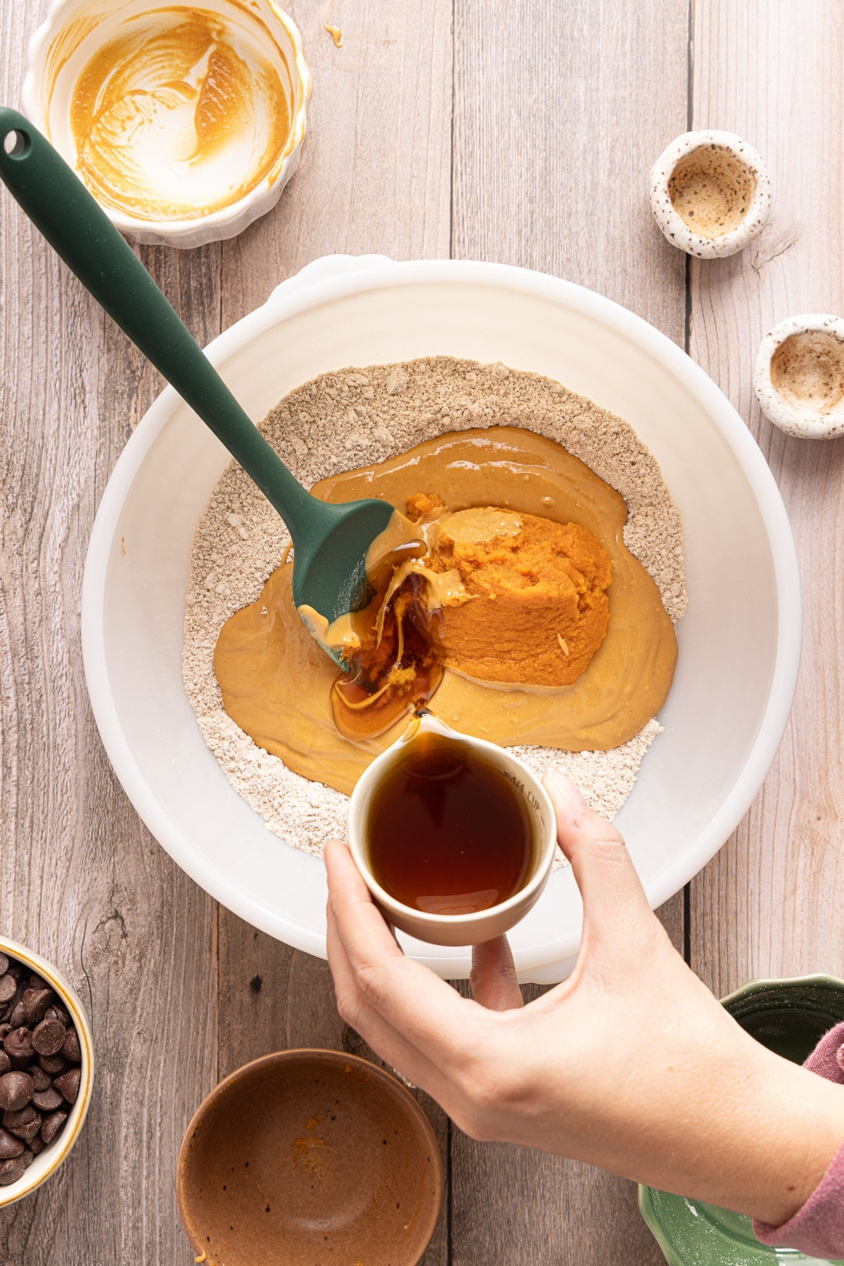 The wet ingredients for the pumpkin oat base in the bowl with the mixed dry ingredients before stirring together.