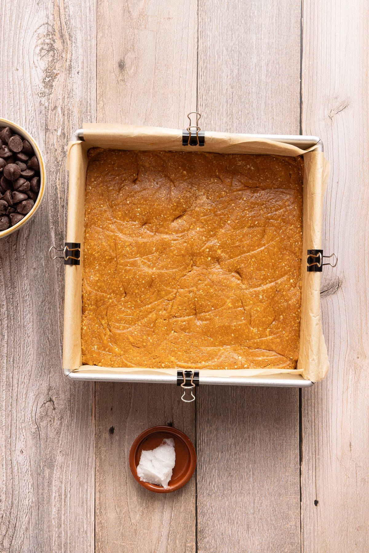 The pumpkin oat base spread out in a square baking dish lined with parchment paper.